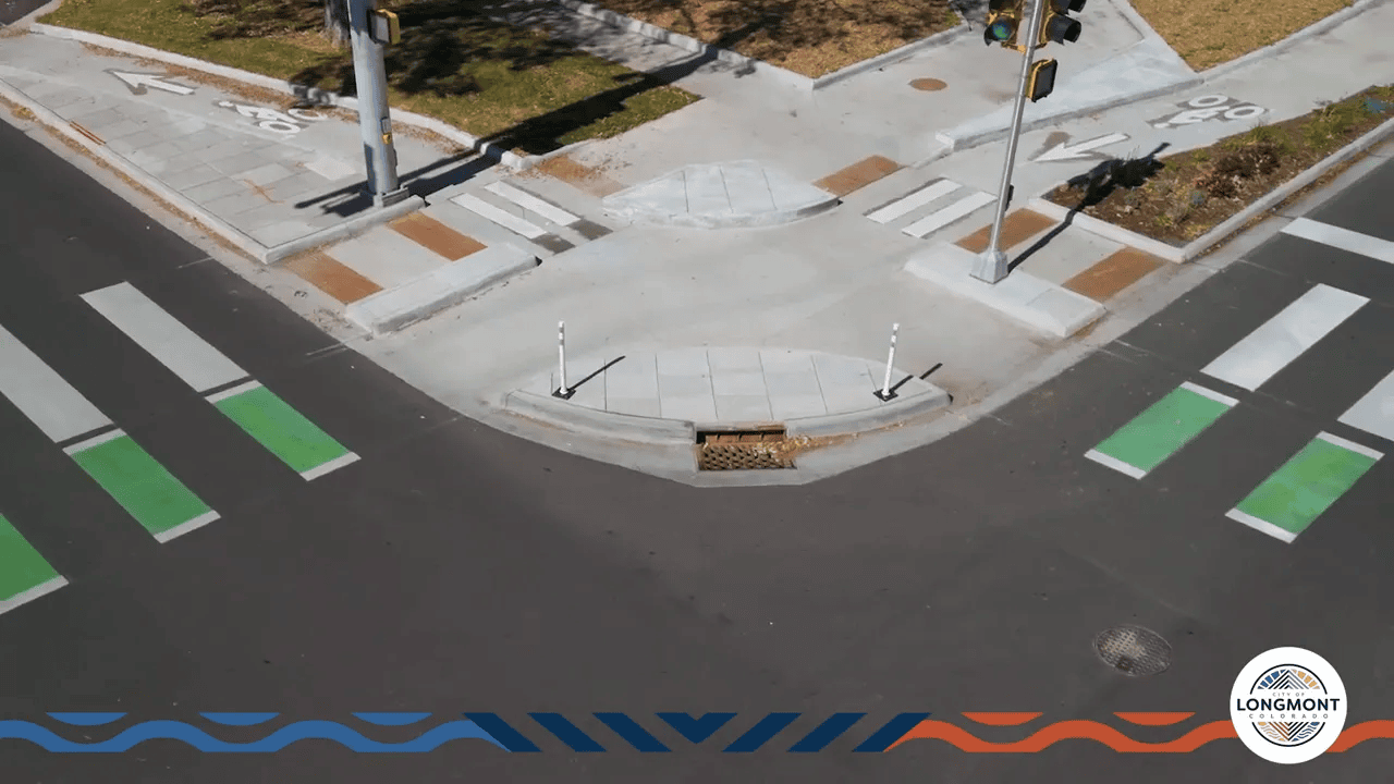 Aerial view of a protected intersection corner island with shortened crosswalks and green bike lane markings in Longmont.