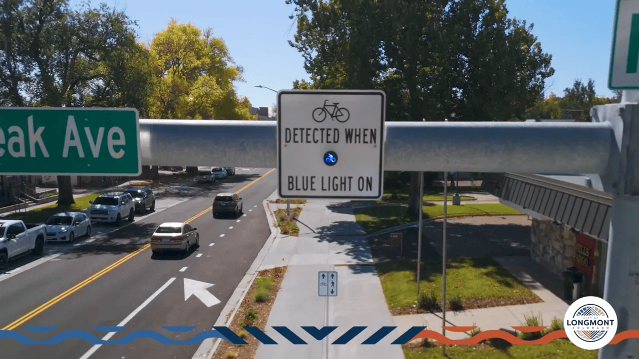 Close-up of a bicycle detection sign with an illuminated blue light over a street